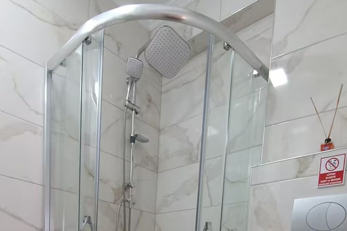 Ein Badezimmer mit einer Duschkabine, einer Toilette und einem Boden aus Marmorfliesen.