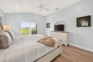 A bedroom with a bed, a dresser, a ceiling fan, and a window with blinds. - Fairway Vista - 3/3 w/ 4-Seat Golf Cart in The Villages - Moultrie Creek (Moultrie Creek, The Villages)