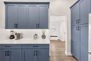 A kitchen with blue cabinets, a white countertop, and a blender. - Fairway Vista - 3/3 w/ 4-Seat Golf Cart in The Villages - Moultrie Creek (Moultrie Creek, The Villages)