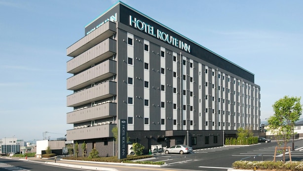 A modern hotel building with a prominent sign, multiple floors, and a parking area. - Hotel Route-inn Yamagata South - in Front of University Hospital (Yamagata)