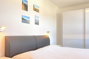 Ett hotellrum med en säng, en garderob och tre tavlor som hänger på väggen.