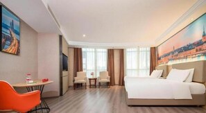 Habitación de hotel con cama, escritorio, dos sillas y un cuadro en la pared.