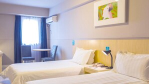 A hotel room with two beds, a desk, a chair, an air conditioning unit, and a painting on the wall. - Jinjiang Inn Huangshan Railway Station Old Street Hotel (Huangshan)