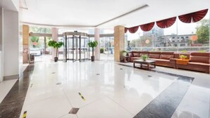 A spacious lobby with a revolving door, seating area, and large windows offering a view of the city. - Jinjiang Inn Huangshan Railway Station Old Street Hotel (Huangshan)