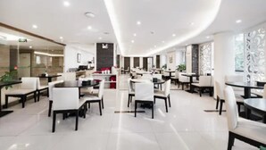 A modern hotel lobby with multiple dining areas, a reception desk, and a curved ceiling design. - Jinjiang Inn Huangshan Railway Station Old Street Hotel (Huangshan)