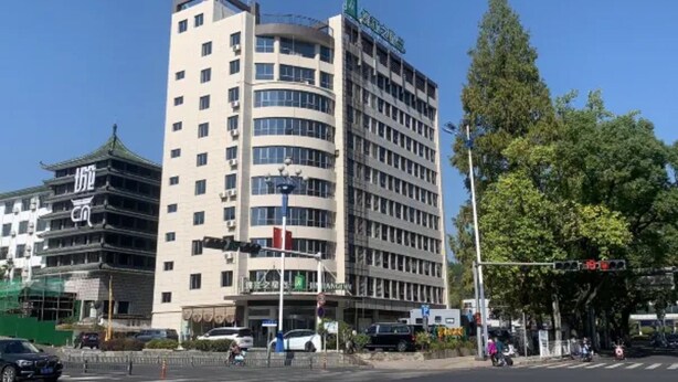 A multi-story hotel with a modern design, featuring a prominent entrance and a parking area. - Jinjiang Inn Huangshan Railway Station Old Street Hotel (Huangshan)