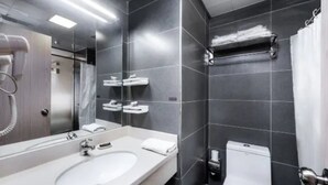 A modern bathroom with a large mirror, white sink, and a toilet. - Jinjiang Inn Huangshan Railway Station Old Street Hotel (Huangshan)