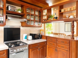 A kitchen with wooden cabinets, a stove, microwave, and a dining area with a table and chairs.