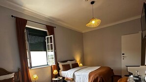 Ein Hotelzimmer mit zwei Betten, Holzboden, einem Esstisch und einer Pendelleuchte.