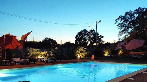 Ein Schwimmbecken mit Holzterrasse, einer dekorativen Lampe und Liegestühlen im Hintergrund.
