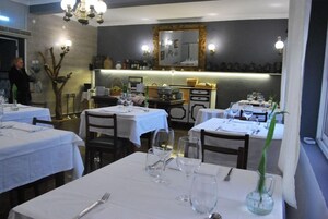 Un restaurante con mesas dispuestas para comer, una zona de bar y un espejo en la pared.