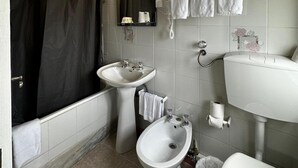 Un baño con una bañera, dos lavamanos, un bidé y un inodoro.