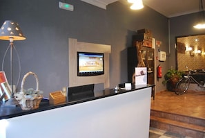 Una recepción con un televisor de pantalla plana, una lámpara, una cesta y una bicicleta al fondo.