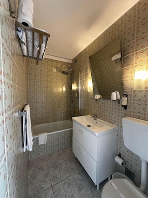 Un baño con bañera, lavamanos, inodoro y zona de ducha.