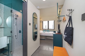 Habitació d'hotel moderna amb dutxa, un llit, escriptori i vista a la ciutat.