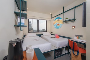 A hotel room with two beds, a desk, a chair, a trash bin, and a window with a city view. - lyf Cebu City (Cebu City)