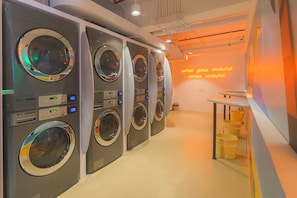 A commercial laundry facility with multiple washing machines and a neon sign on the wall. - lyf Cebu City (Cebu City)
