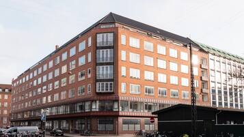 A multi-story building with a corner entrance, large windows, and a parking area with bicycles.