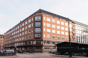 A multi-story building with a corner entrance, large windows, and a parking area with bicycles. - Scandinavian Residence Near the Lakes (København)