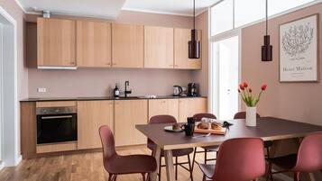 A modern kitchen with wooden cabinets, a dining table with chairs, and a coffee machine.