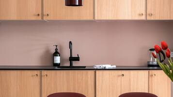 A kitchen with wooden cabinets, a black countertop, a bottle of shampoo, a hairdryer, and red tulips.