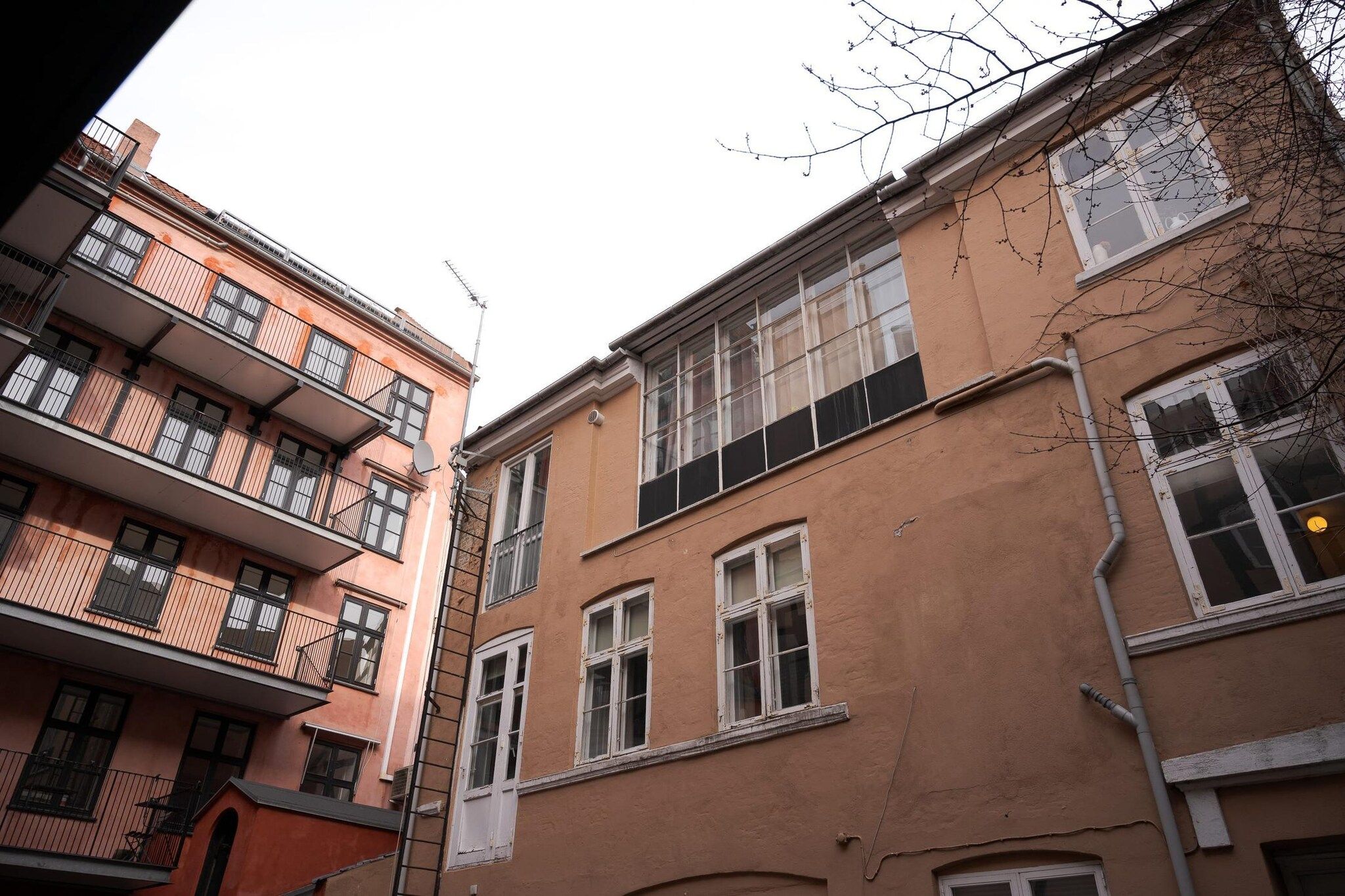 A multi-story building with balconies, large windows, and a visible satellite dish.