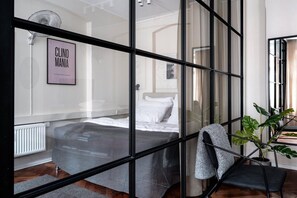 Een moderne slaapkamer met een bed, een radiator, een ingelijst kunstwerk aan de muur en een potplant.