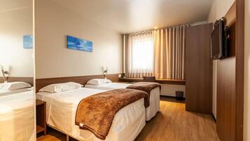 Quarto de hotel com duas camas, televisão, janela com cortinas e uma obra de arte na parede.