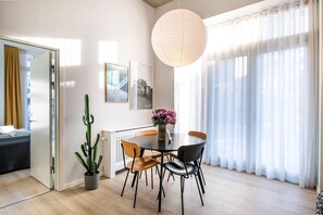 Uma área de jantar moderna com mesa redonda, cadeiras, planta de cacto e obras de arte nas paredes.