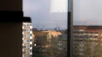 A view through a window of a building with multiple floors, a clear sky, and distant industrial structures.