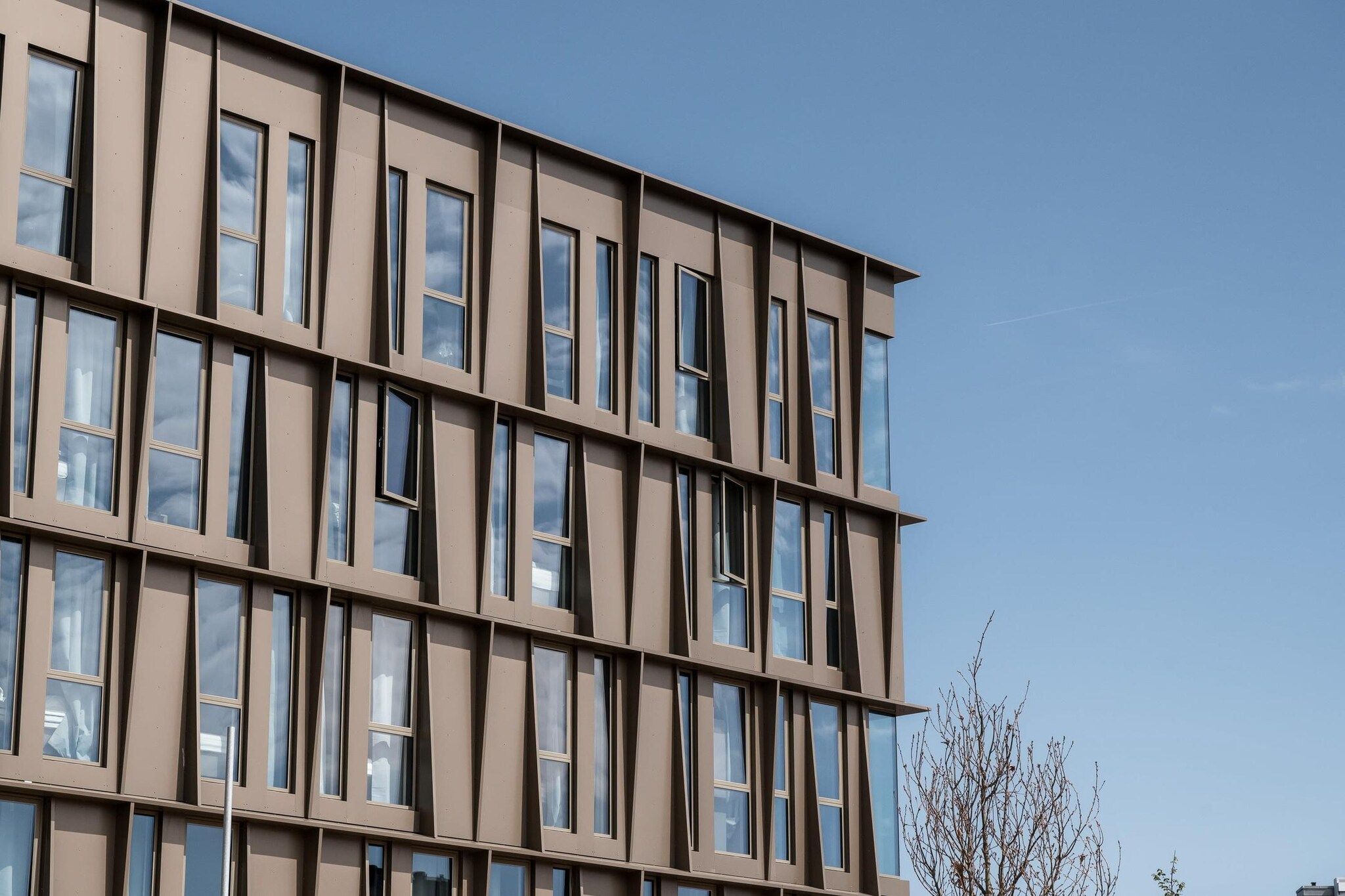 A multi-story building with a modern architectural design, featuring a grid of windows and a flat facade.
