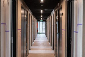 A long corridor with doors on both sides, leading to a bright exit at the end.