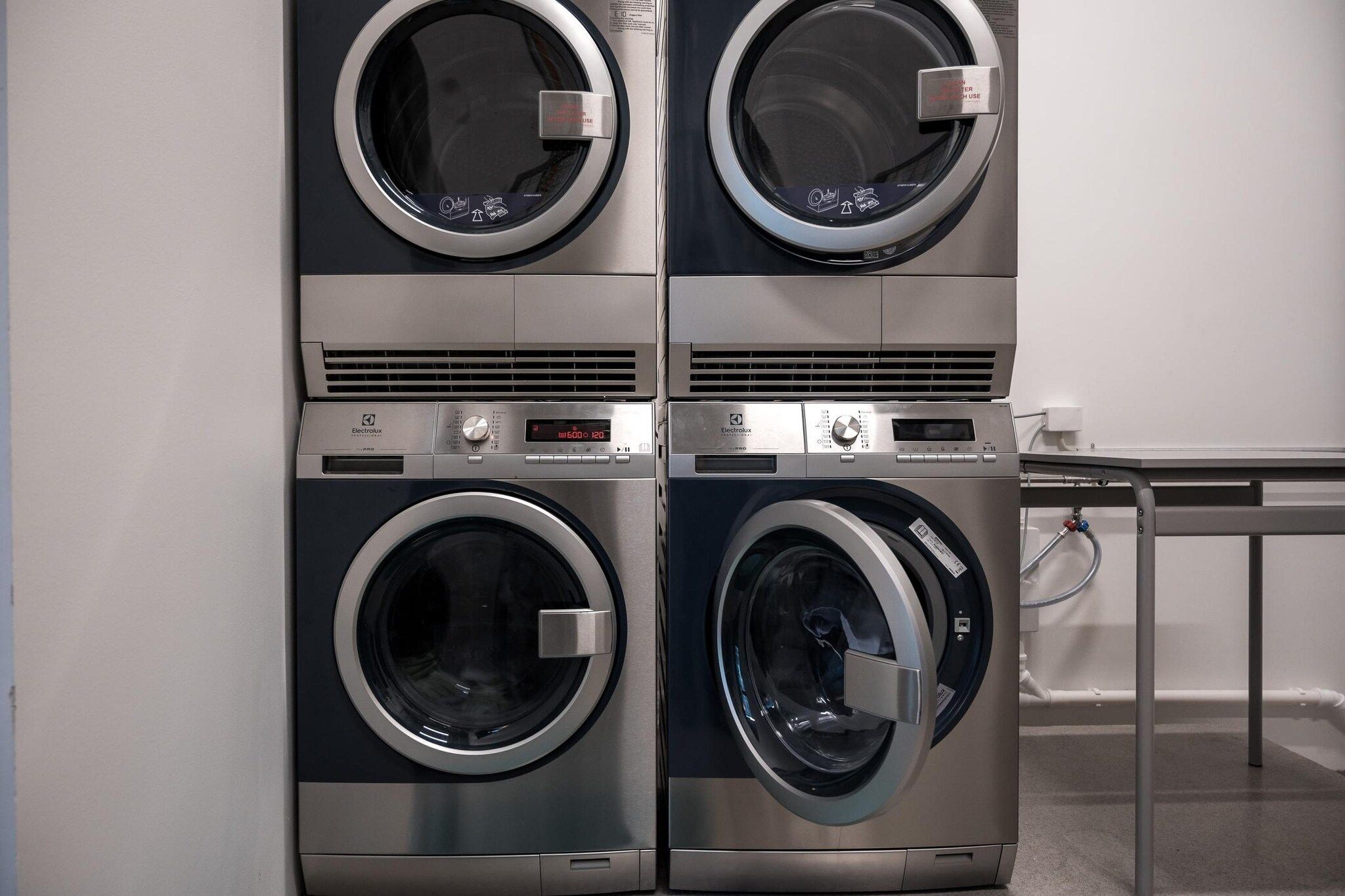 A four-door wall-mounted washer and dryer unit with control panels and a digital display.