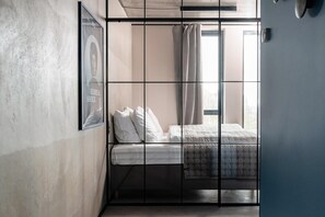 Una habitación con una cama, un cuadro en la pared y una ventana con cortinas.