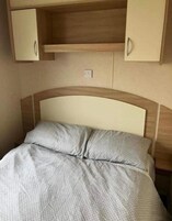 Una cama con cabecera y dos mesitas de noche en una habitación.