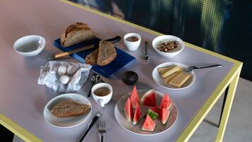 Una tavola imbandita per la colazione, con pane, uova, caffè e fette di anguria.