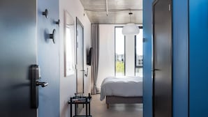 A hotel room with a bed, a desk with a chair, a desk lamp, a telephone, and a window with curtains. - Cityside Apartment in Aarhus (Aarhus)
