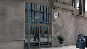 A building entrance with a glass door, a signboard, and a potted plant. - Cityside Apartment in Aarhus (Aarhus)