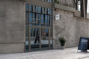Ein Gebäudeeingang mit Glastür, einem Schild und einem Blumentopf.