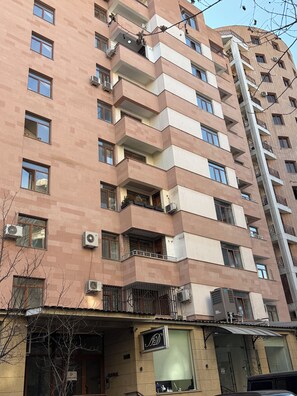 Ein mehrstöckiges Wohnhaus mit Balkonen, Klimaanlagen und einem Geschäft im Erdgeschoss.