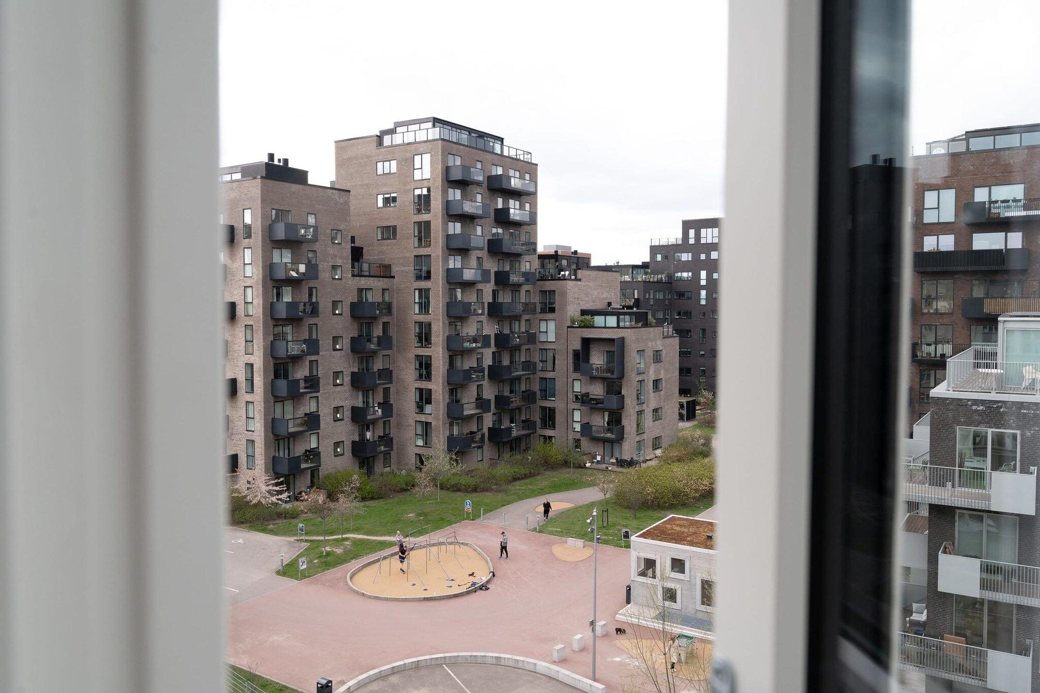 A high-rise residential building with multiple balconies and a central courtyard with a playground.