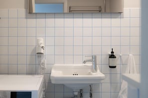 A bathroom with a white sink, a towel rack, and a bottle of hand soap. - Coastal flat in Amager with pool (København)