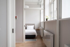 A modern bedroom with a bed, bedside table, and a radiator. - Coastal flat in Amager with pool (København)