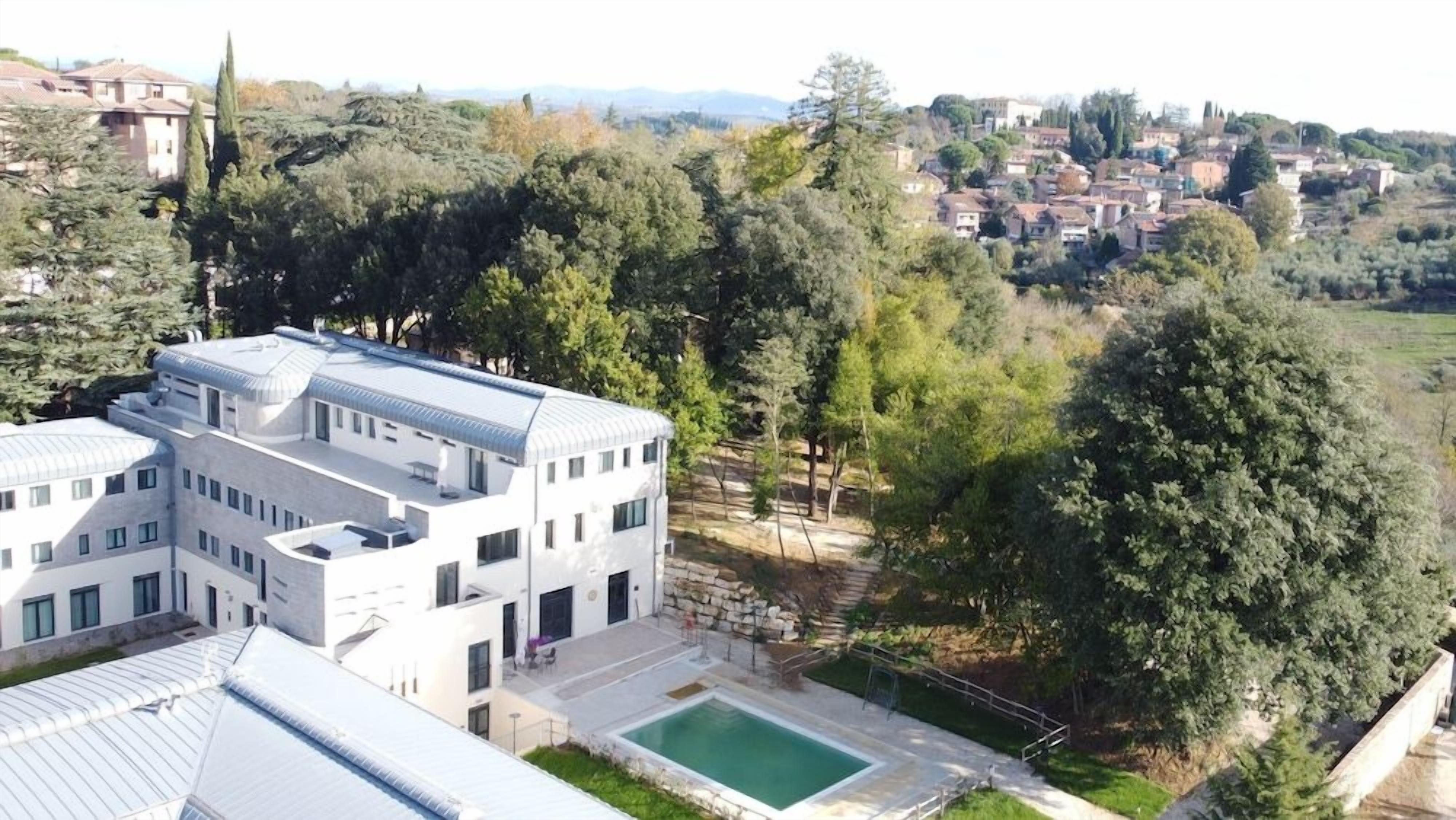 Un edificio moderno con piscina, immerso nel verde e con panorama collinare.