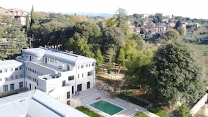 Un edificio moderno con piscina, rodeado de árboles y un paisaje montañoso.