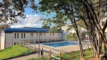 Un edificio con piscina, circondato da una recinzione in legno e alberi.