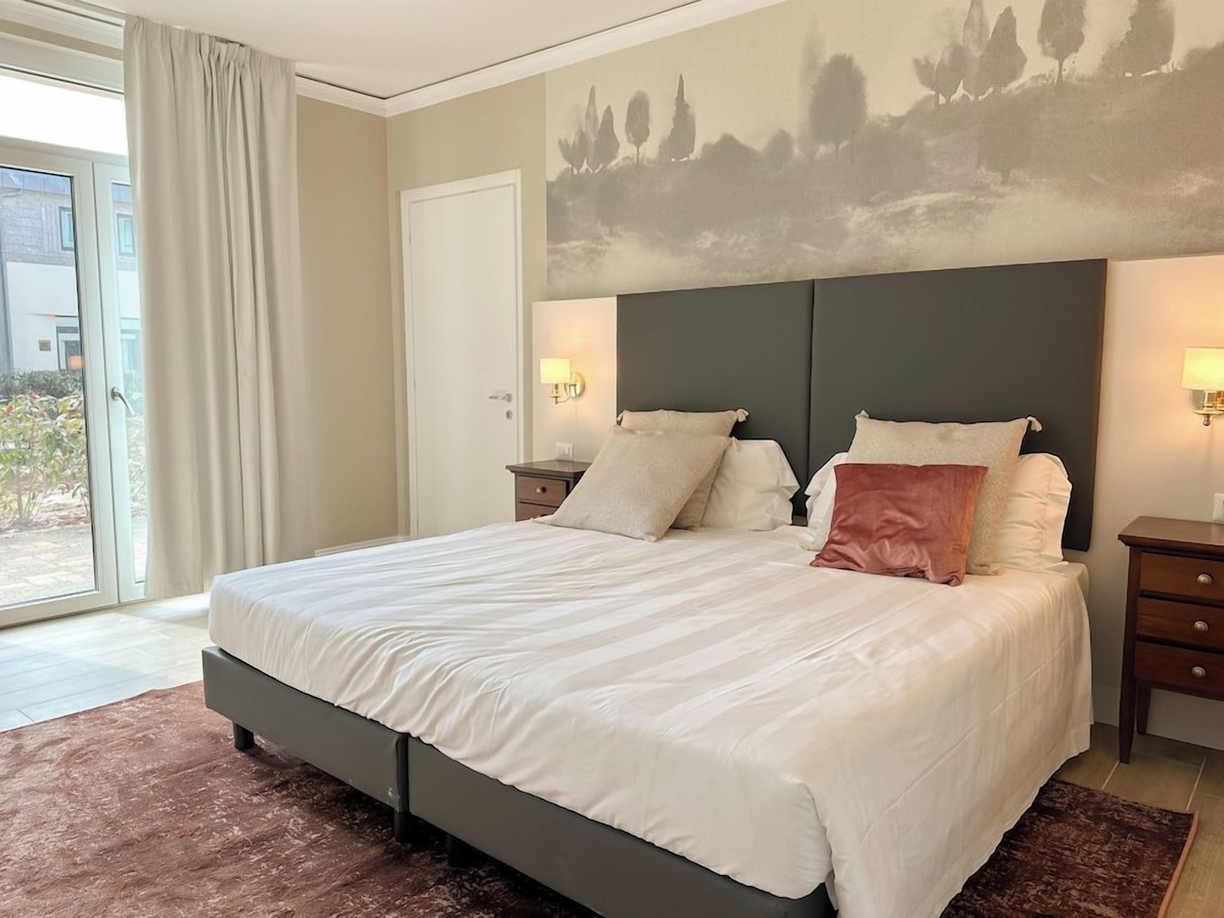 Una camera da letto con un letto grande, due comodini, una testiera e vista sull'esterno.