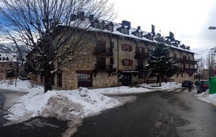 Un edificio de piedra con múltiples ventanas y balcones, rodeado de nieve.