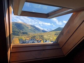 Un tragaluz con vistas a un paisaje montañoso y un pueblo en la falda.