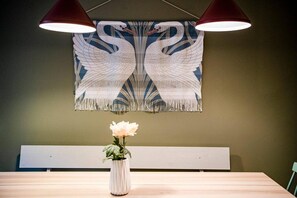 A dining area with a table, a vase with flowers, and a wall tapestry. - Home Near Buses and Metro (København)
